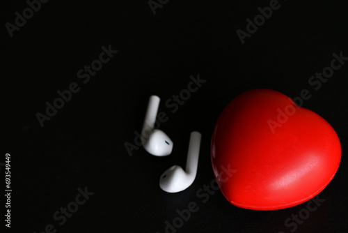 Audífonos inalámbricos como parte del tratamiento para sanar problemas del corazón, concepto de musicoterapia. Espacio para texto al lado izquierdo