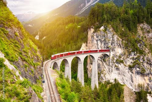 Swiss red train on viaduct in mountain, scenic ride photo