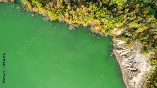 This image is taken from an aerial perspective  capturing the graceful curve of a river as it winds through a lush landscape. The vibrant green waters contrast starkly with the rocky embankment to one
