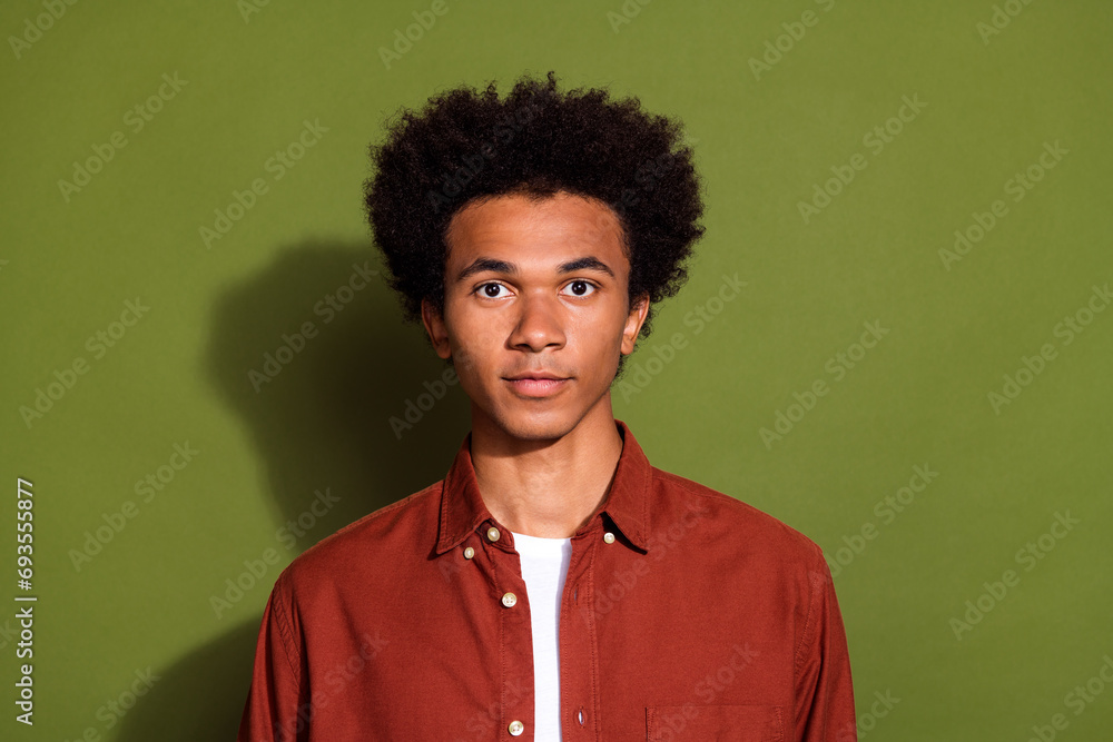 Photo of good mood serious confident man with afro hairstyle dressed brown shirt looking at camera isolated on khaki color background Photo of good mood serious confident man with afro hairstyle dressed brown shirt looking at camera isolated on khaki color background