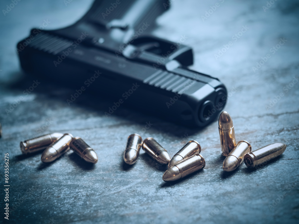 Hand gun with ammunition on dark background. 9 mm pistol military weapon and pile of bullets ammo at the metal table. Hand gun with ammunition on dark background. 9 mm pistol military weapon and pile of bullets ammo at the metal table.