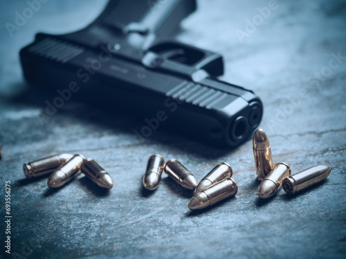 Hand gun with ammunition on dark background. 9 mm pistol military weapon and pile of bullets ammo at the metal table. photo