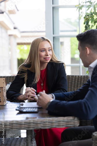 Blonde estate agent shares available house variants with positive client. Realtor offers ideal variant of residence to businessman