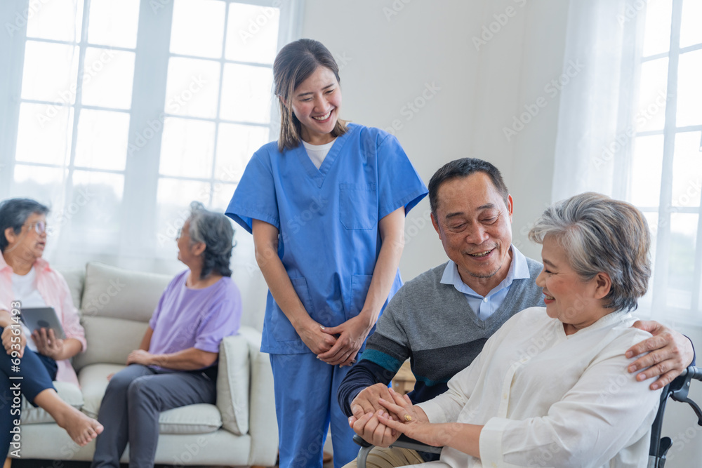 Fototapeta premium Asian young nurse support couple senior older man and woman in a wheelchair. elderly mature and a group of senior friends living in the hospital. socializing of retired people.