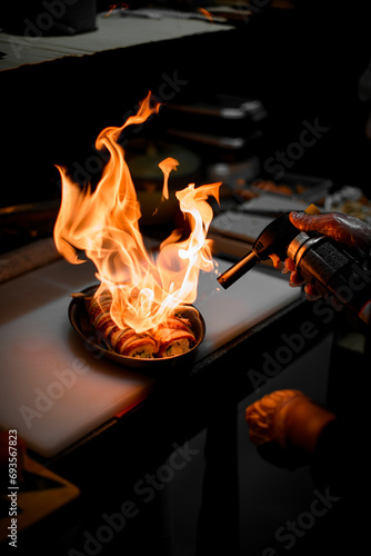 Chef frying sushi rolls in an oval shape using a gas burner