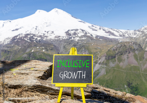 Inclusive growth symbol. Concept words Inclusive growth on beautiful black chalk blackboard. Beautiful mountain Elbrus blue sky background. Business inclusive growth concept. Copy space. © Dzmitry