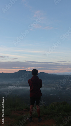 A male climber is enjoying the morning atmosphere at the top of Arang hill photo