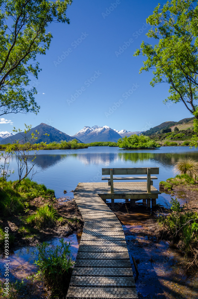 Tranquil scene at Glenorchy, New Zealand with bench and footpath visible at the at the lake.