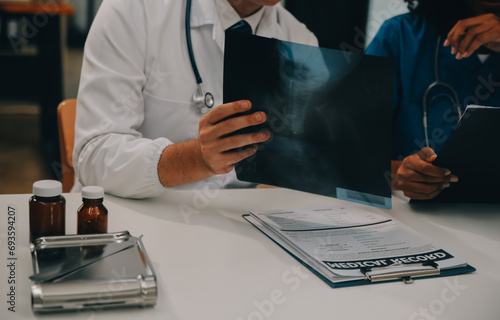 Focused mature male doctor and female nurse look at tablet screen discuss anamnesis together. Concentrated diverse medical professionals use pad device, engaged in team thinking in hospital.