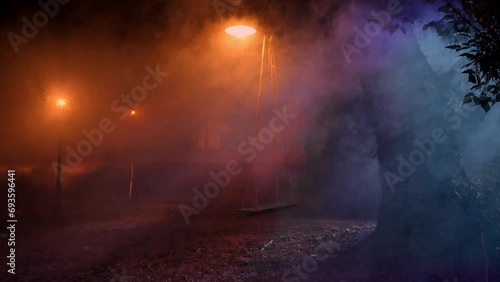 Altalena in giardino avvolta nella nebbia della notte illuminata da dei lampioni con casa sullo sfondo  in 4K photo