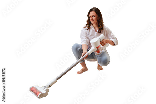 Happy woman with a wireless portable vacuum cleaner in the kitchen, isolated on a white background. A smiling woman cleans the floor in an apartment with a vacuum cleaner with a battery