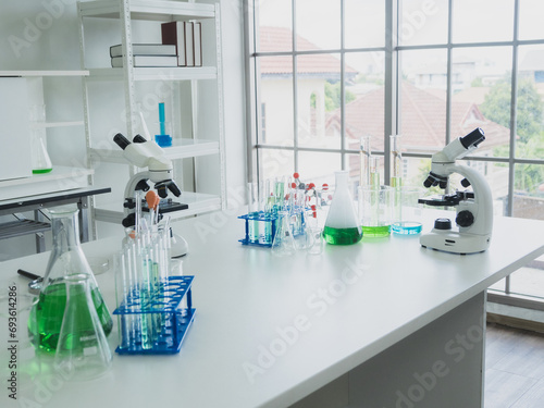 scientific instruments beaker test tube and microscope for analyze scientists was placed on white wooden table with research reagents in the bright white room for study and work health medical
