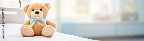 Cute teddybear toy on patient bed at hospital. Health center or hospital room for young patient. Healthcare and childhood concept photo