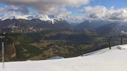 Chairlift and ski slopes in Pescasseroli with the Marsicani mountain range in the background, Abruzzo, Italy.  photo