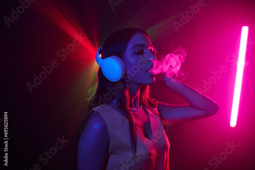 Young woman enjoying night life, she is dancing in headphones and smoking
