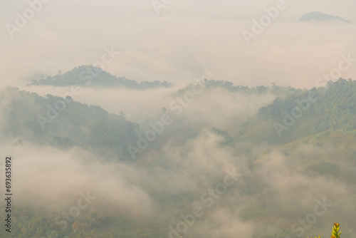 The stunning view from a tourist's standpoint as they go down a hill on a foggy trail with a hill and a background of a golden sky in Forest Park, Thailand. Bird's eye view. Aerial view. 