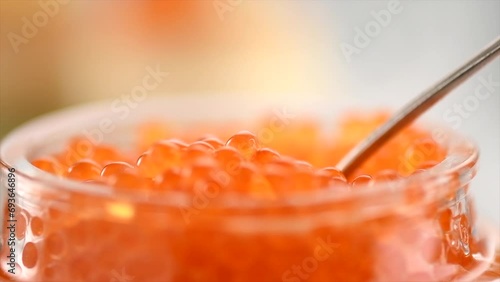 Red Caviar in a spoon, fish roe background. Close-up of salmon fish eggs caviar. Delicatessen. Texture of trout caviar close up. Seafood. Slow motion.  photo