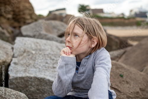 Behang The thoughtful expression of a 10-year-old boy as he sits pensively on the sizab