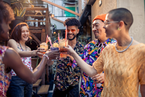 Multiracial group of happy friends drinking cocktails in bar photo