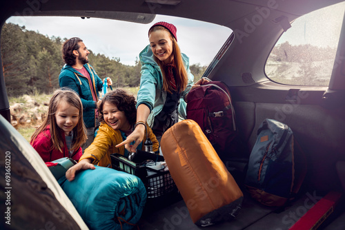 Family taking camping gear out of car photo