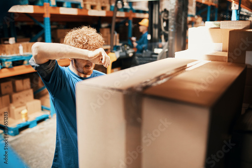 Tired young man working in warehouse photo