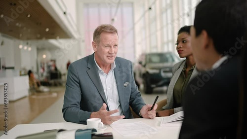 Salesman giving a car key to couple at dealership