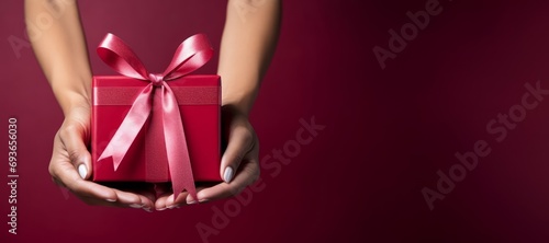 hands holding gift box on red background, gift concept for loved ones, space for text photo