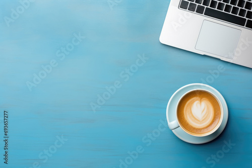 top view of a minimalist workspace featuring a sleek laptop and a cup of coffee on a vibrant blue background, with free space for text or advertising photo