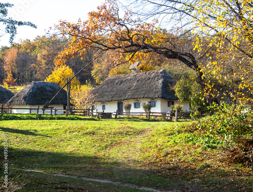 Traditional wooden houses with thatched roof and white walls. A small houses in village, Ukraine. Picturesque village in autumn.