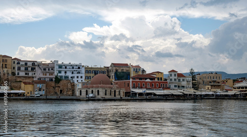 Chania Town Crete, Greece. Panoramic view of outdoors cafe, seaside building and church. Ripple sea.