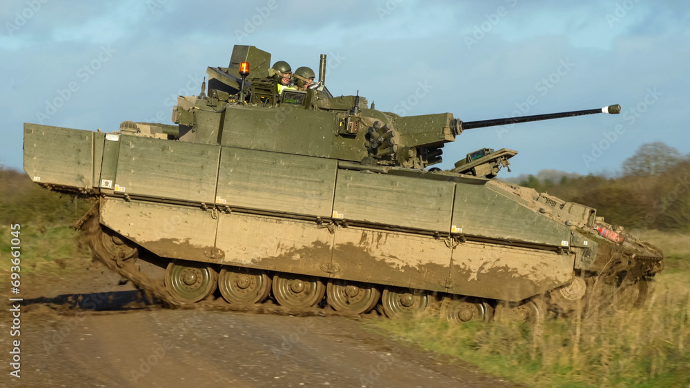 British army General Dynamics Ajax Reconnaissance and Strike armoured fighting vehicle (AFV), tank in action, crossing a track. Wilts UK