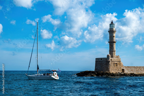 Lighthouse at Venetian harbour in Old Town of Chania Crete Greece. Boat sailing in ripple sea water. © Rawf8