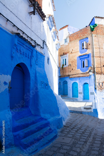 Narrow street with some houses with old doors, all painted blue in the medina of Chefchaouen, Morocco © Vicente Sargues