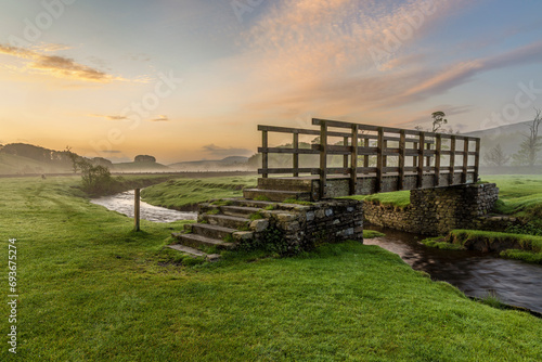 Fototapeta Naklejka Na Ścianę i Meble -  Sunrise at the footbridge over Gayle Beck near the picturesque market town of Hawes in the Yorkshire Dales
