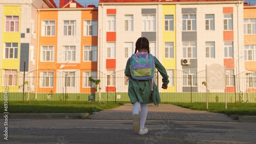 little girl with school backpack runs with her feet way to school. child daughter hurries knowledge lesson. heavy school bag shoulders running kid child. school childhood. children running outdoors.