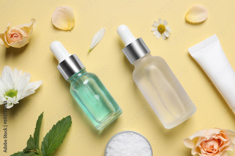Flat lay composition with cosmetic serums on pale yellow background Flat lay composition with cosmetic serums on pale yellow background