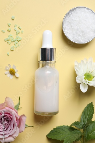 Flat lay composition with cosmetic serum on pale yellow background