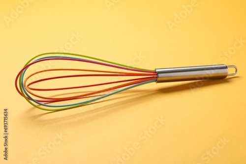 Bright whisk on yellow background. Kitchen tool