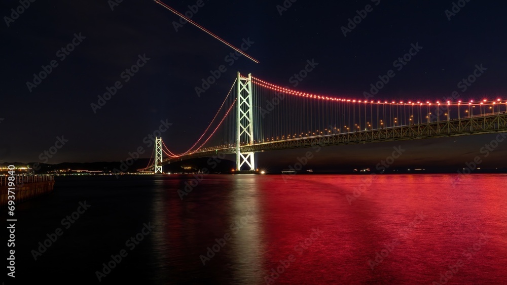 ライトアップされた明石海峡大橋と赤く染まる水面のコラボ情景