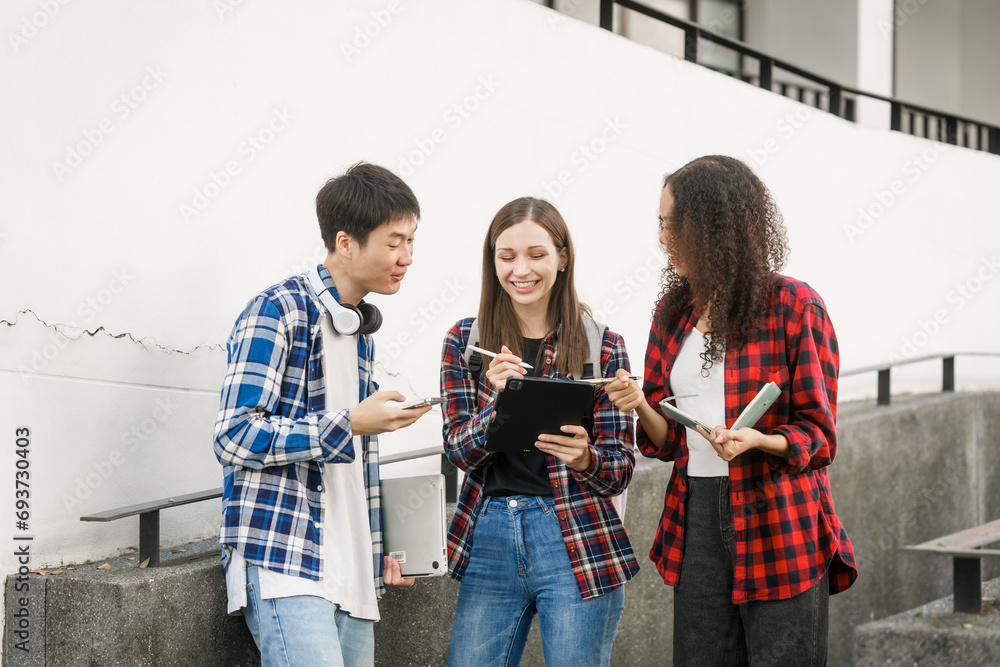 Group of young interracial diverse university students chatting together outside, engaging in a discussion together, college campus, enjoying campus recreation. Happy friends