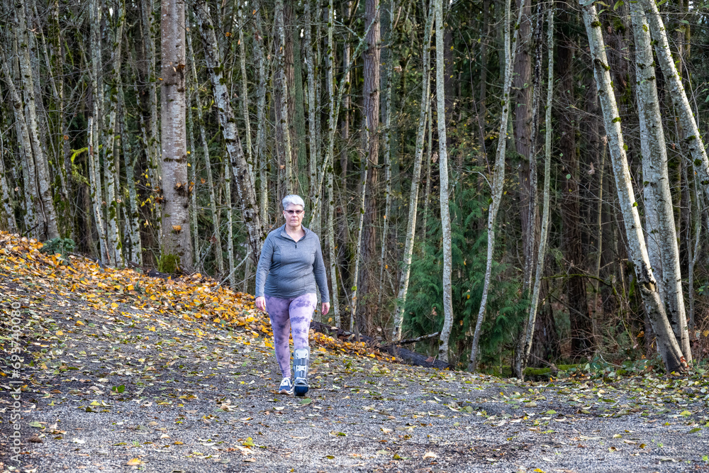 Middle aged woman with gray hair and a foot injury out for a walk on a sunny winter day, active with a boot, soft cast, on her foot
Middle aged woman with gray hair and a foot injury out for a walk on a sunny winter day, active with a boot, soft cast, on her foot