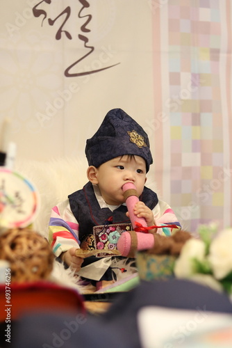 Celebrating Korean traditional 1st year birthday party with a grand ceremony called 'Doljanchi' (돌잔치). 1 year old Korean boy playing the highlight of the ceremony called 'Doljabi' (돌잡이). photo