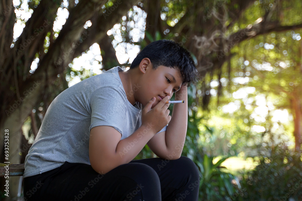 A teenage boy secretly comes to sit and smoke alone in a hidden corner of the school. which is the substance use behavior of teenagers who have life problems. soft and selective focus. A teenage boy secretly comes to sit and smoke alone in a hidden corner of the school. which is the substance use behavior of teenagers who have life problems. soft and selective focus.
