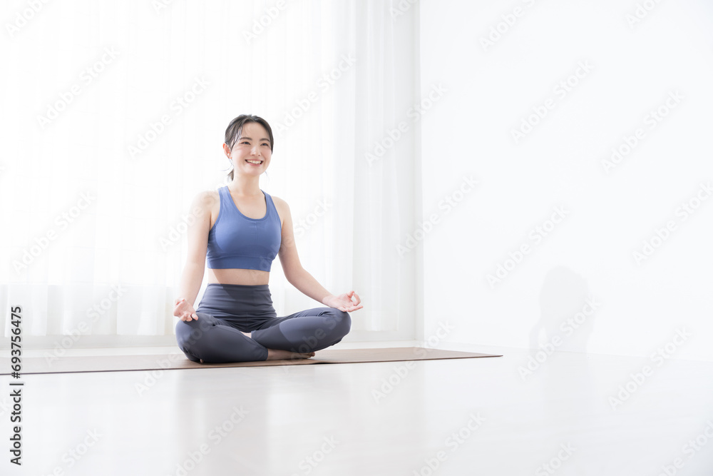 Young woman doing yoga, Sukhasana, wide angle Young woman doing yoga, Sukhasana, wide angle