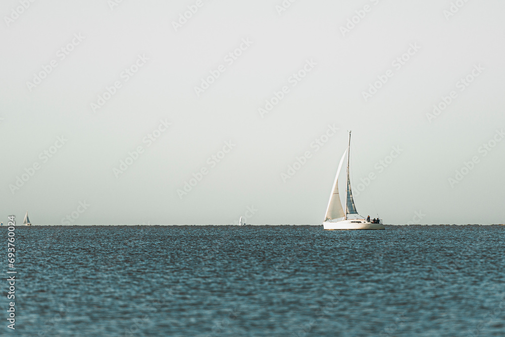 Barco blanco navegando en un mar tranquilo y azul, con un horizonte marcado y hermoso.