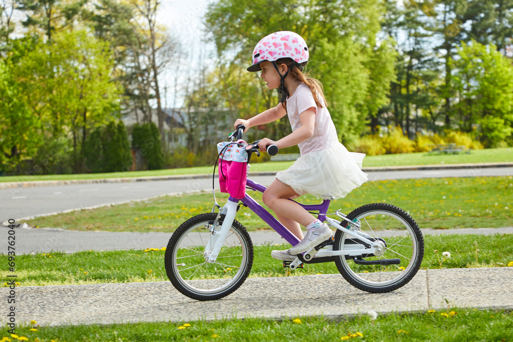 Cute little girl riding her first bike with a helmet on having fun on her new two wheeler Cute little girl riding her first bike with a helmet on having fun on her new two wheeler