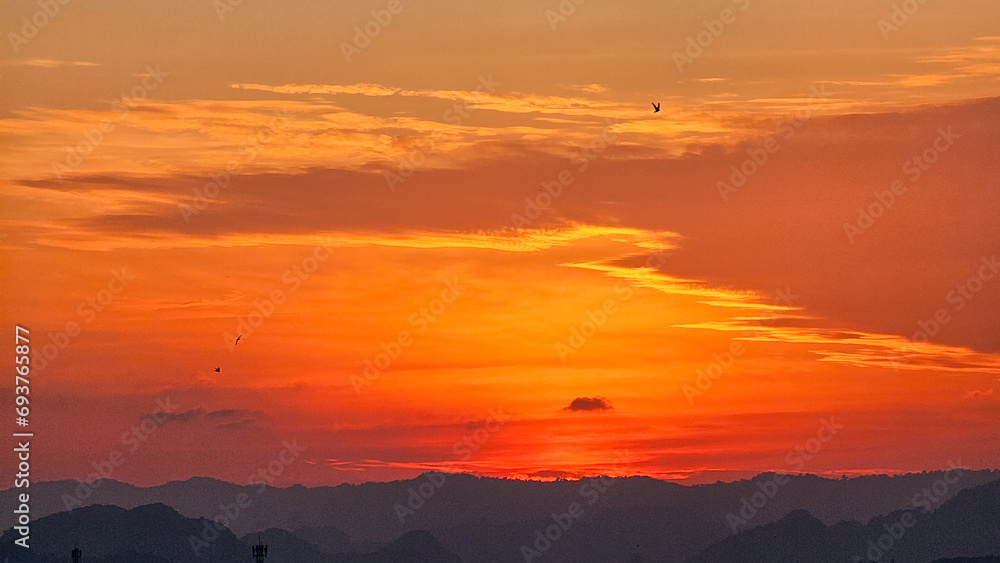 Beautiful sunset in the mountains. Sunset with beautiful orange evening sky and silhouette of mountains. Dramatic sunrise. Orange Sky. Bird in sky