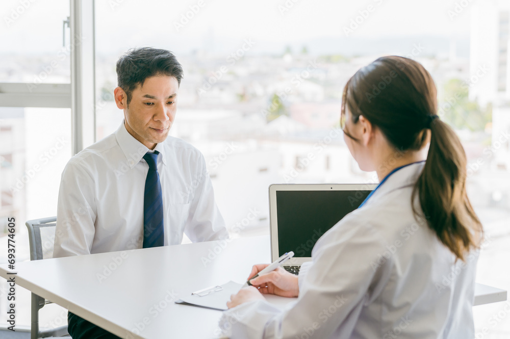 病気の病名告知をされてショックを受ける男性と医者
