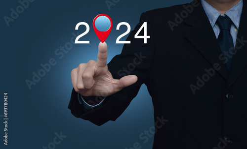 Businessman pressing 2024 letter with map pin location icon over light blue wall, Happy new year 2024 map pointer navigation concept