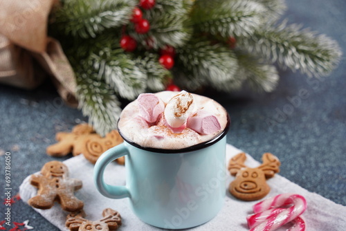 Hot cocoa with marshmallow in a mug surrounded by winter things on a wooden table. The concept of cozy holidays and New Year.